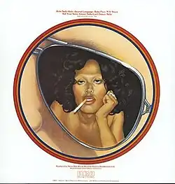 An album cover features a white background and red text, too low resolution to read. The central image in a red circular frame is a close-up of an aviator sunglass lens showing a woman posed, sultry, leaning her head on her hand with a cigarette hanging from her mouth. A cloud of dark hair surrounds her and her shoulders are bare.