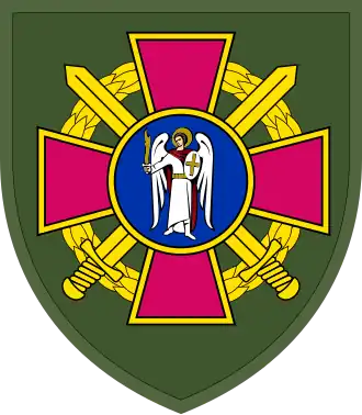 Arm badge of the Kyiv City Territorial Center of Procurement and Social Support, with an angel in front of two crossed swords on a dark green backdrop