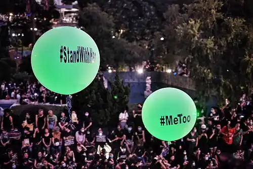 Hashtag #StandWithHer and #MeToo in large balloons