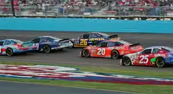 Tony Stewart (of Joe Gibbs Racing) is getting involved in a close battle for position against several other drivers.