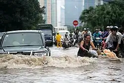 People and cars travel through a flooded street in Hanoi.