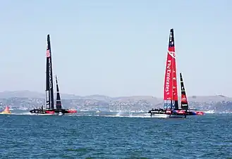 Color photograph of a racing catamaran underway with the starboard hull out of the water