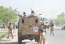 Armed soldiers in and around a military vehicle