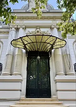 Wrought iron door with a glass and metal awning at the top, at the entrance of the George Deșliu House on Bulevardul Dacia, Bucharest, by Ernest Doneaud, 1912[53]