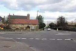 mini-roundabout beside a long, low, 2-storey stone cottage with yellow-painted window frames