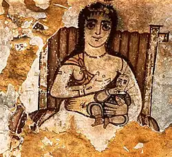 Painting of a seated woman with a child in her lap, offering one of her breasts to the child