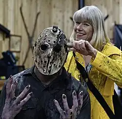 A behind the scenes picture of the fan film Jason Rising (2021) with an actor in costume as Jason, on the left, and actress Adrienne King, right, in costume as Alice