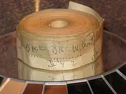 An aged roll of paper tape perhaps 1–2 inches (2.5–5.1 cm) wide; on the outside is written "BASIC 8K without cassette" and "July 2" in blue biro pen.