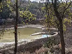 a small with caked mudflat arount it, and a tall great blue heron standing at the edge