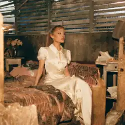 Grande sitting on a bed