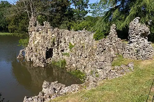 A colour photograph of the side of an island with a rocky outcrop of grey-brown limestone