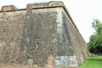 Curtain wall in the corner, or counterguard, made of ashlars with marks of cannonball impacts and embrasures for rifles