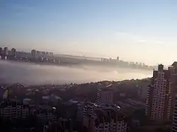 Low-lying fog, with an otherwise clear sky. The fog covers the relatively less densely urbanized lowlands while avoiding urban areas and hills.