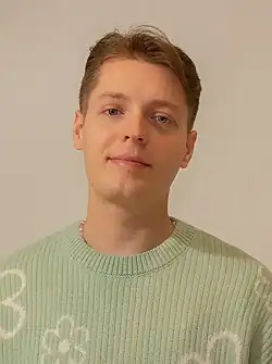 Head shot of Dolic wearing a light green sweater