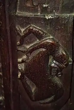 Dark wooden carving in the shape of a medieval depiction of a horse