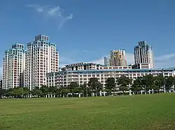 Apartment blocks of varying heights behind a field