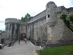 A colour photograph of the wall and a gate of an imposing late Medieval stone castle
