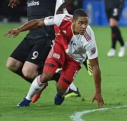 A soccer player is running. He is slightly off-balance and is leaning forward