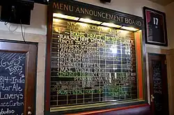 Blackboard with labels for names of train and destinations, but lists names of beers and other beverages instead