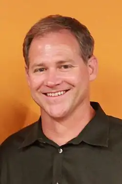 Brian Dunning smiling against a orange background
