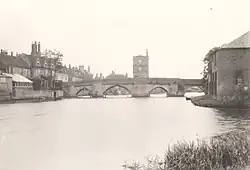Photograph of an arched bridge over the river, with a rectangular chapel building in the centre