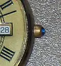 A round sapphire cabochon on the crown of a men's dress watch.