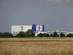A mostly white large building styled after a crate of Capri-Sun: It has blue towers at two corners with "Capri-Sun" on both outer sides at their peaks; midway along both visible sides, there is an image of an Orange-flavor Capri-Sun pouch.