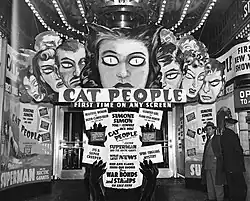 An entrance to a movie theatre adored with display art featuring people with demonic eyes and promotional text for Cat People.