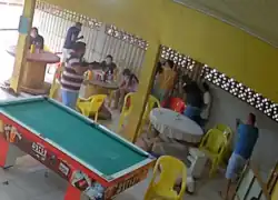 In a pool parlor, one man holds a rifle and the other holds a pistol. They are pointing them at people. Those people, including children, appear scared.