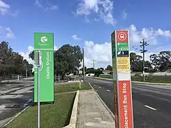 Tall bus stop pole with signage on it on the side of a road