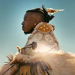 Two photos of Chief Xian aTunde Adjuah overlaid on one another with him wearing Native American garb