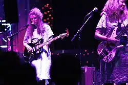 Band members play music onstage while wearing hospital gowns.