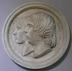 commemorative silver-coloured medallion showing left profiles of Clara and Robert Schumann