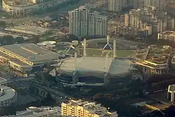 Aerial view of a lit-up convention centre at dusk, with high-rises as the backdrop.