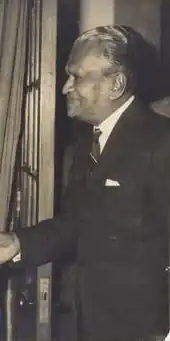 Black and white photo of D. P. Atapattu wearing a suit, facing to another person who has been cropped out