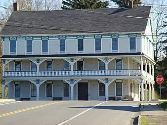 A three-story white building with a full-length second-story balcony, blue trim and a black roof