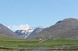 A farm set in a valley with lots of green grass surrounding it