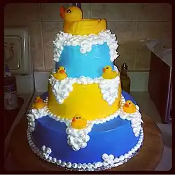 Yellow and blue three-tier cake decorated with rubber ducks