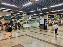 People walking at the station concourse level, with faregates that separate the paid and unpaid areas.