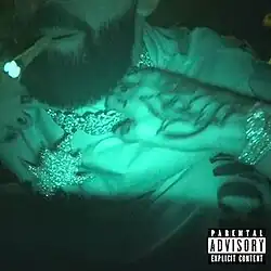 A night-vision colored image of a man holding his chain, whilst smoking a blunt.