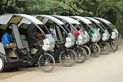 a row of electric rickshaws with a couple of people inside