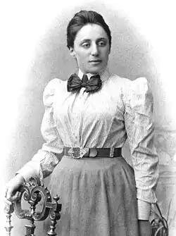 Portrait of Emmy Noether in her 20s with her hand resting on a chair
