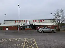 Image of the front of the arena stand, showing the car park and front doors