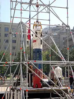 color image of the Phoenix 2 capsule held upright by scaffolds in a central square on display in Santiago, Chile