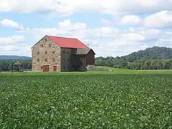 A three-story fieldstone barn with a red roof