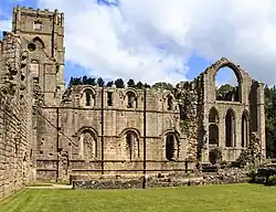 The ruined walls of a large abbey with a tower