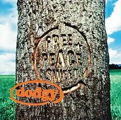 A closeup of a tree trunk in a field with the album's title engraved on it