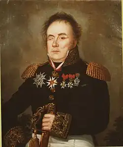 Portrait shows a man wearing a dark blue military uniform with a number of awards pinned to the coat. His right eye is closed by an injury.