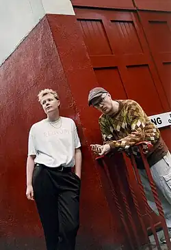 Ed Tullett and Jemima Coulter in front of a red wall