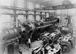 Under assembly c.1890, half of one of the two 10,000&nbsp;hp engines completed for Deptford Power Station at Hick, Hargreaves and Co.[115][116][117][118] A travelling crane and hoist above.